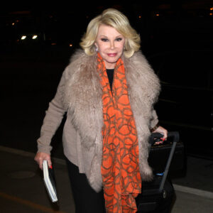 Joan Rivers smiles in orange scarf at LAX